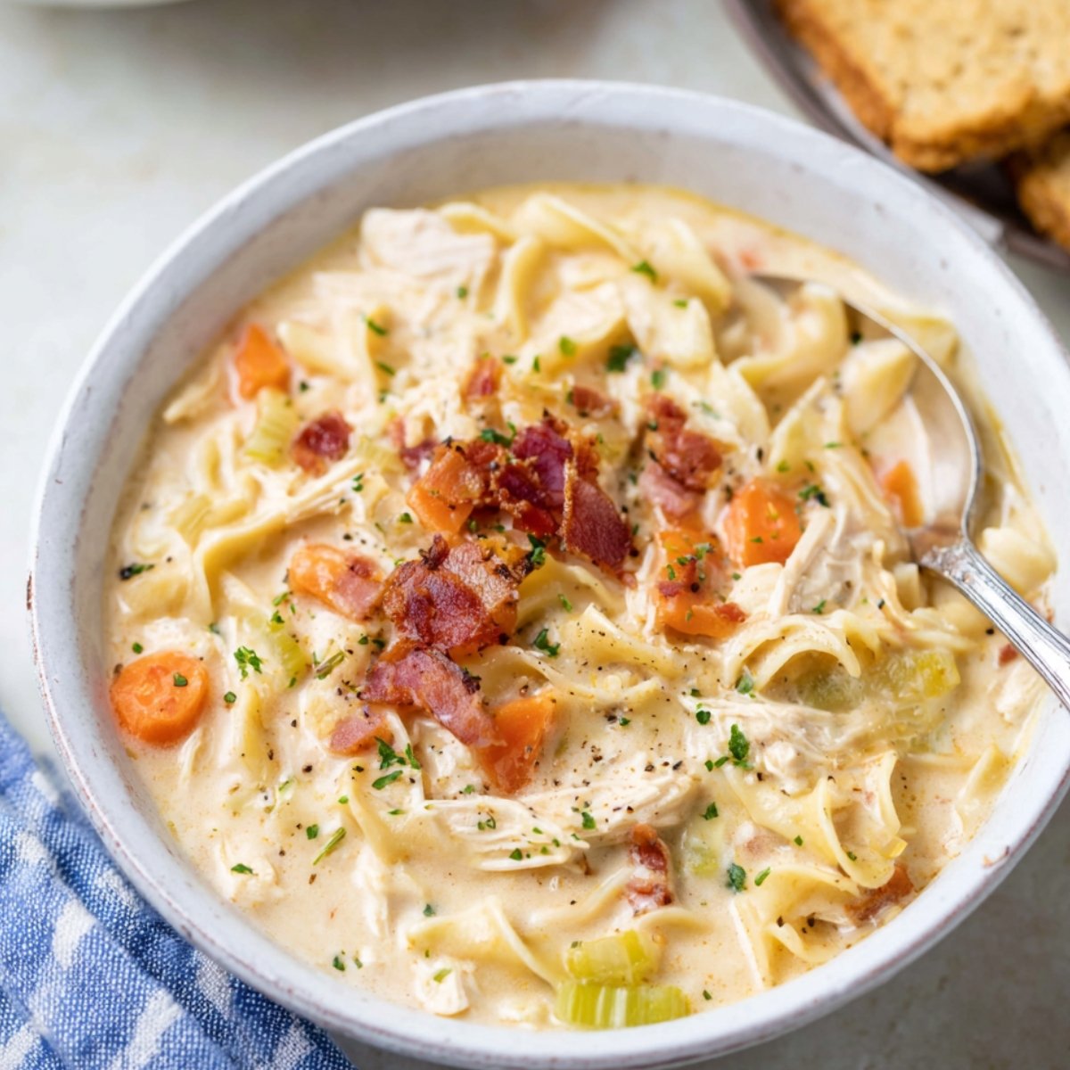 Bowl of creamy Crack Chicken Noodle Soup with noodles, bacon, and vegetables