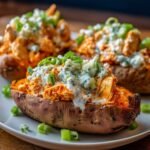 Homemade Buffalo Chicken Stuffed Sweet Potatoes on a white plate, topped with ranch, blue cheese, and green onions, warm natural light, homemade and cozy.