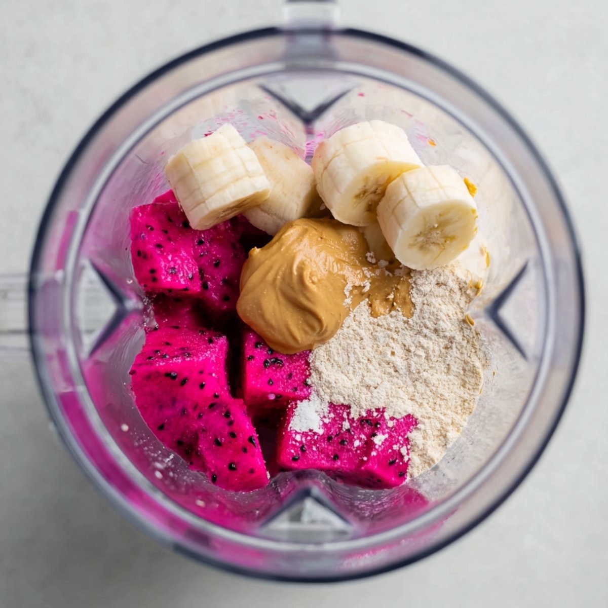 Place the almond milk, frozen dragon fruit, frozen banana, protein powder, and almond butter into a high-speed blender. Put the liquid in first so the blades can move easily.
