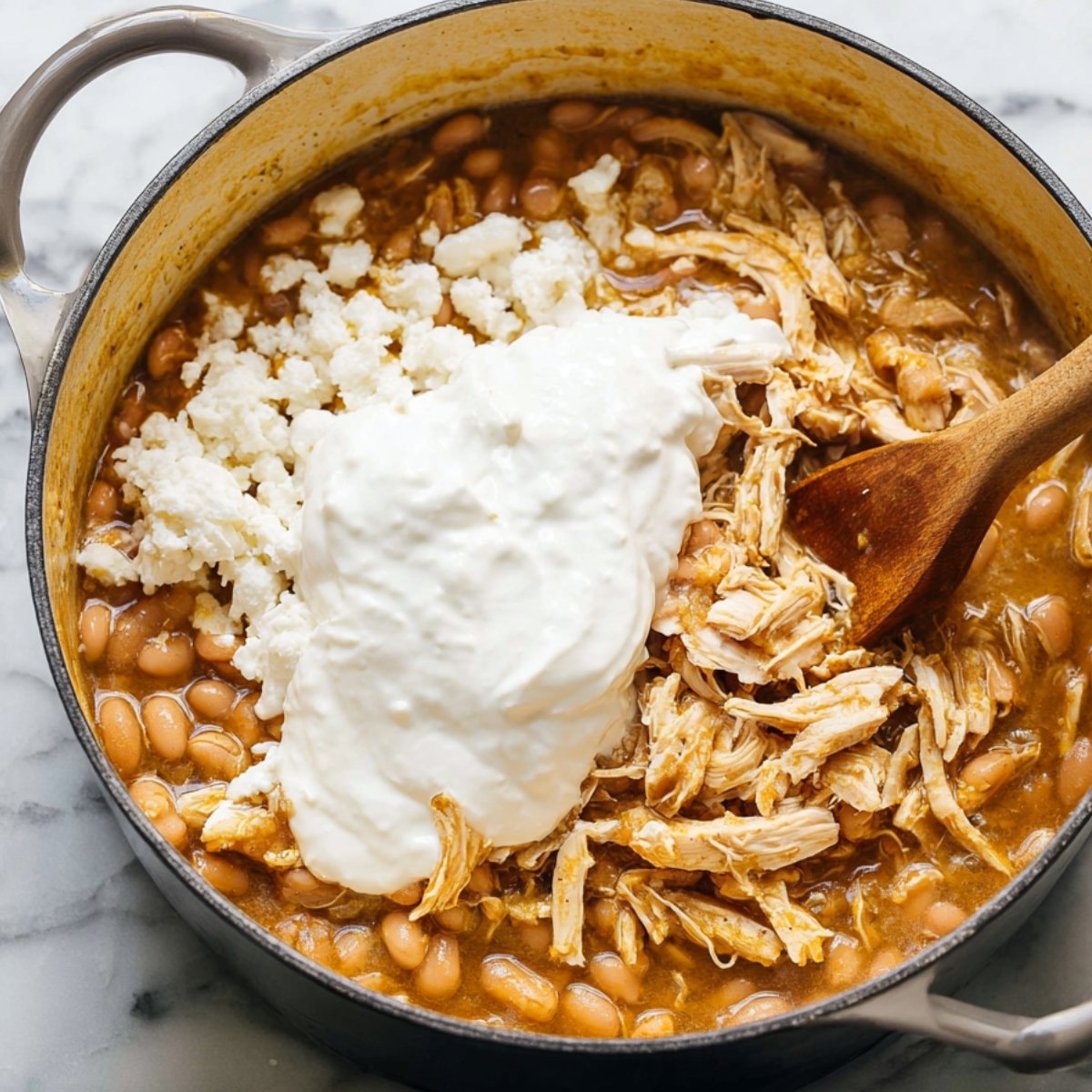 Remove the pot from the heat. Stir in the sour cream until it's completely mixed in and the chili turns creamy and pale, then fold in your shredded chicken. Taste and add more salt or lime juice if needed.