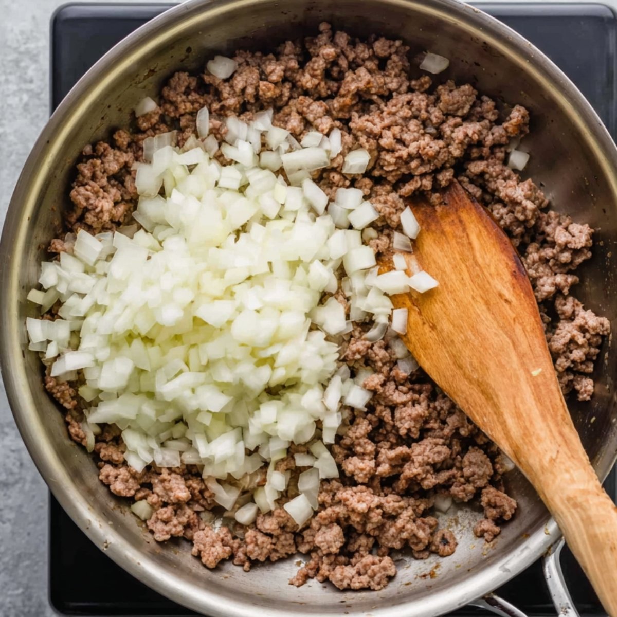 Add the ground beef and break it into small pieces as it cooks. Toss in the diced onions and minced garlic, and sauté everything until the onion turns translucent and golden brown. You'll start to smell that amazing garlicky aroma filling your kitchen.