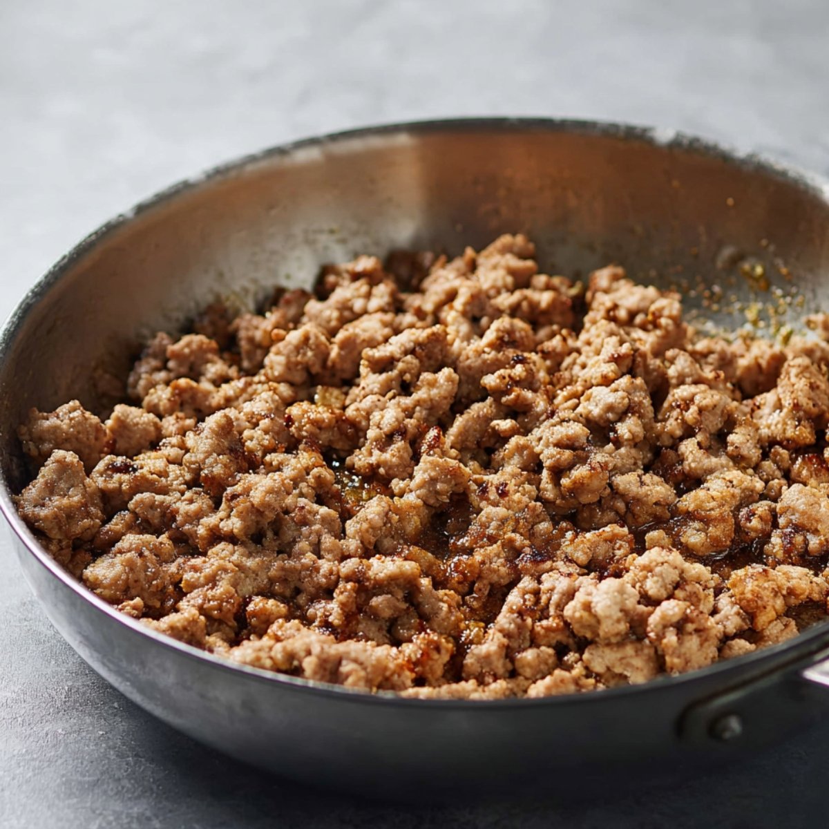 Crumbled ground meat browning in a skillet.