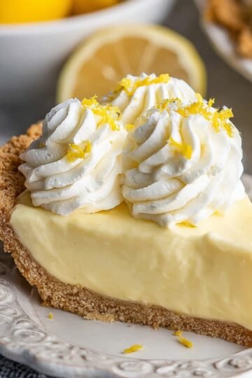 Creamy Lemon Cream Pie with a golden, flaky crust and a smooth, creamy filling, sitting on a white plate.