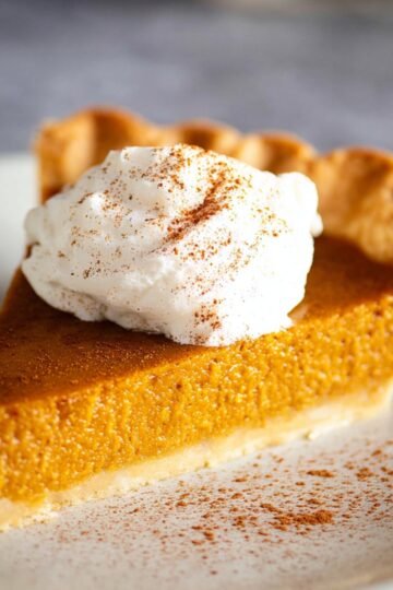 Homemade Pumpkin Pie with a dollop of whipped cream and a dash of cinnamon.