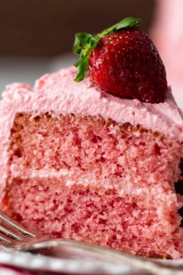 Homemade Strawberry Cake with pink frosting and fresh strawberries.