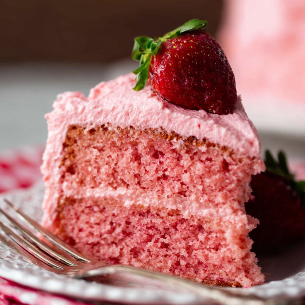 Homemade Strawberry Cake with pink frosting and fresh strawberries.