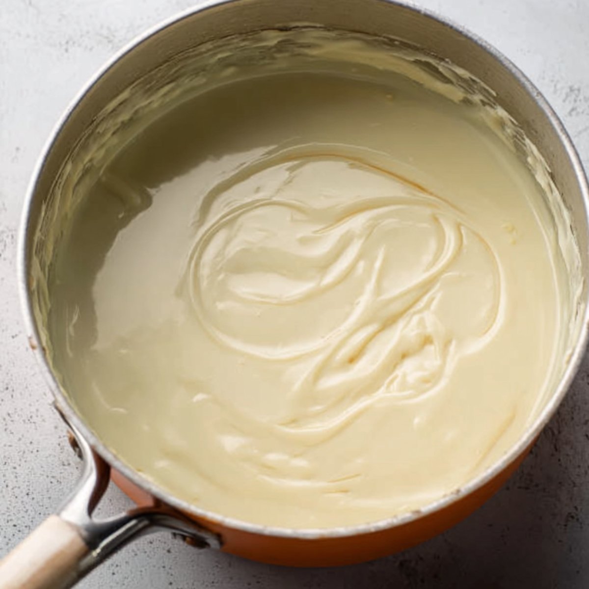 A thick, smooth lemon filling in a saucepan, showing a pale yellow color with a glossy texture.