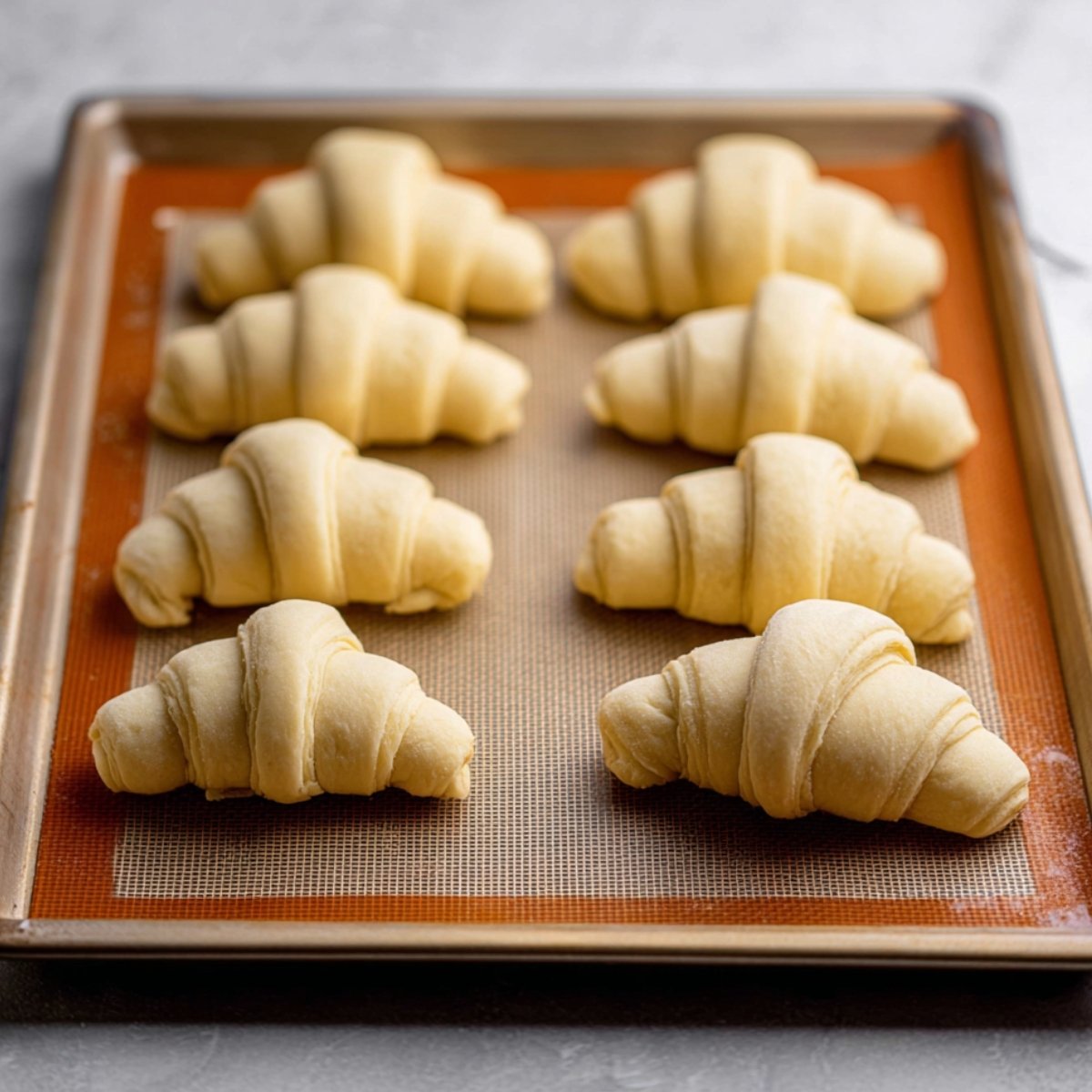 Shaped croissants on a baking tray, ready for the final rise.