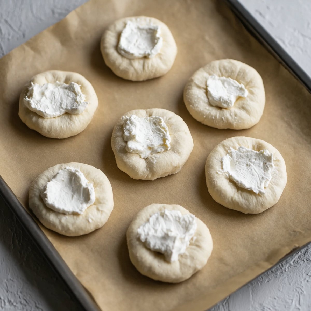 Bagel dough rounds with a dollop of cream cheese in the center, set to be folded into stuffed bagel bites.