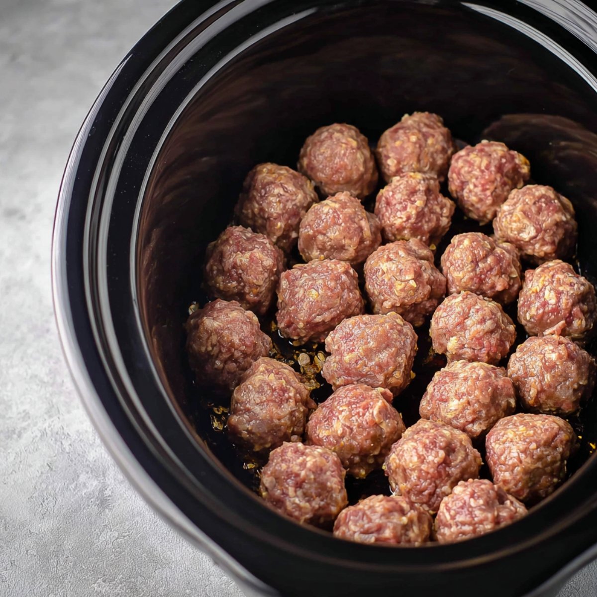 Once they're done baking, move the meatballs to your slow cooker. Drain off any excess fat from the sheet tray first.